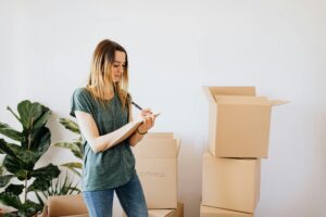 Woman with a clipboard next to piles of boxes